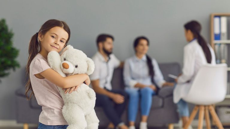 parents et un enfant tenant un gros nounours en peluche chez le medecin