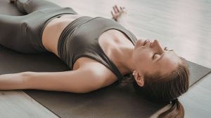femme allongee sur dos  sur tapis de gym en etirement