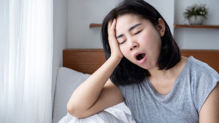 femme qui baille assise sur son lit