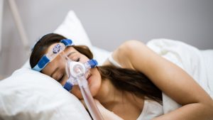 femme dans son lit avec appareil apnee du sommeil
