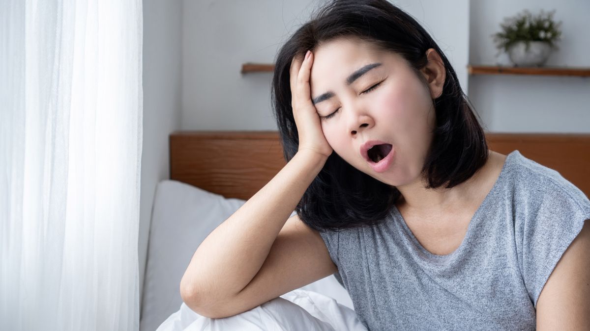 femme qui baille assise sur son lit