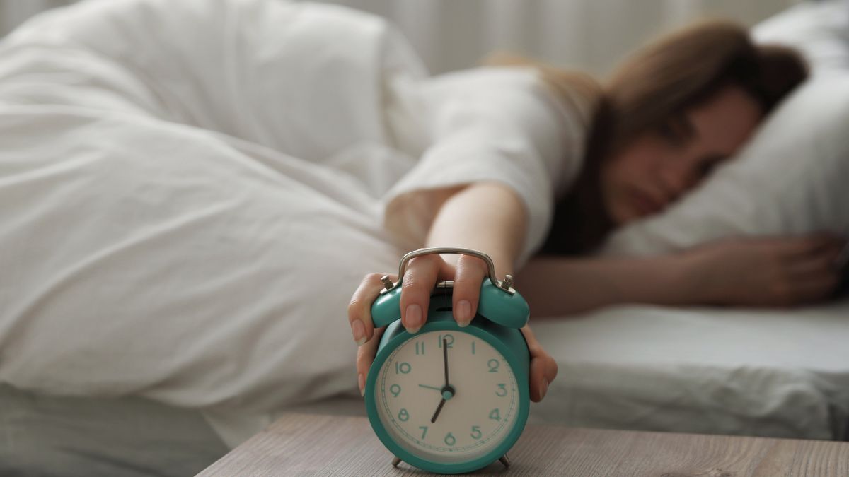 femme au lit tenant son reveil matin
