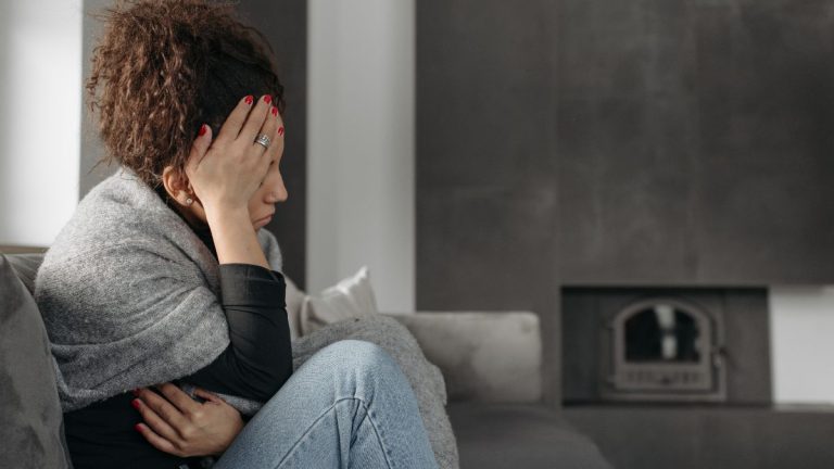 femme assise recroquevillee avec douleurs tête et ventre