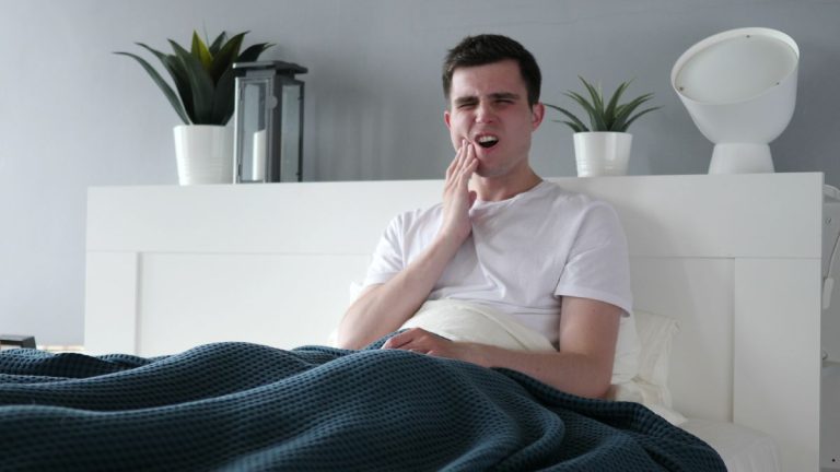 homme dans son lit qui a mal a sa machoire