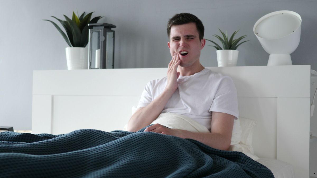 homme dans son lit qui a mal a sa machoire