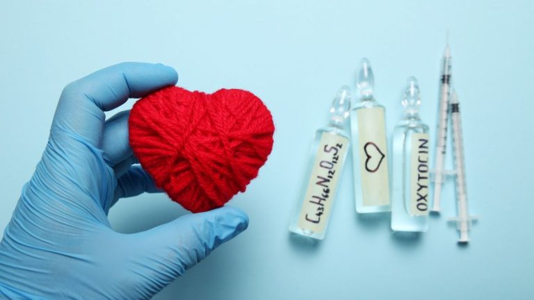 main gantee tient un coeur rouge avec flacons ocytocine et seringues
