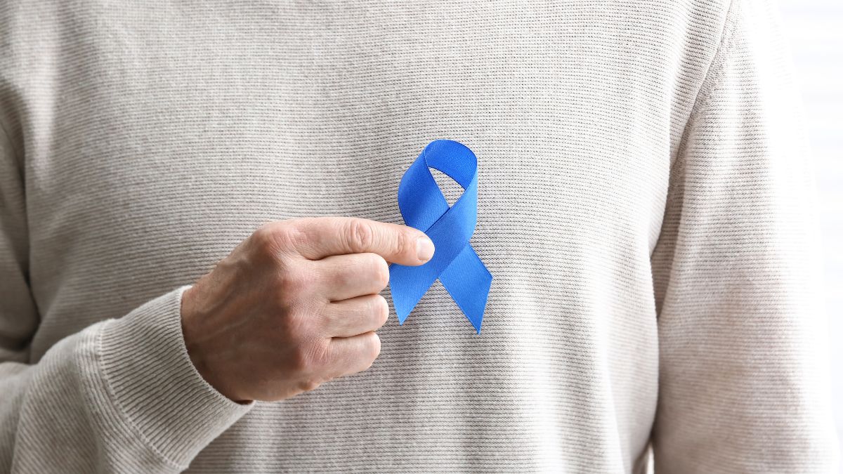 un homme tient un noeud bleu cancer colorectal